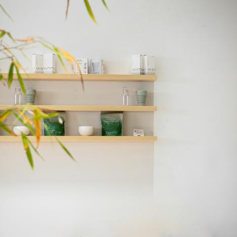 Drie lichte houten wandplanken met verzorgingsproducten aan een witte muur