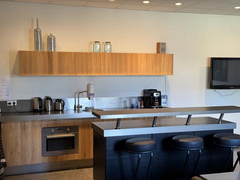Moderne keuken met houten keukendeurtjes, geribbelde wandkast, kookeiland en zwarte barkrukken