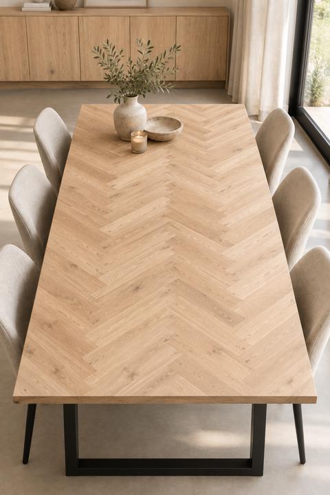 Massief houten tafelblad in visgraatpatroon met zwarte metalen poten en beige eetkamerstoelen