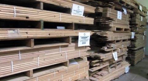Stapels massief houten panelen en planken op pallets in het magazijn van WoodStock