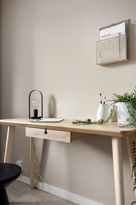 Licht houten bureau met lade en taps toelopende houten tafelpoten in een stijlvol interieur