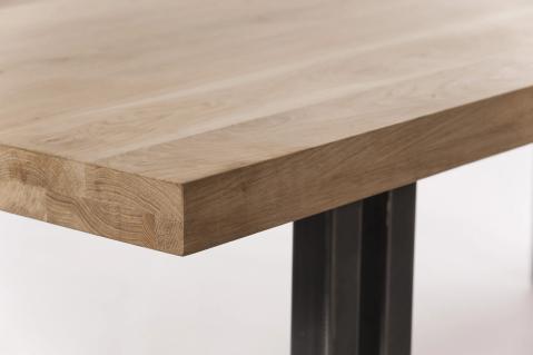 Detail van een massief eiken tafelblad met zichtbare houtnerf en zwart metalen onderstel