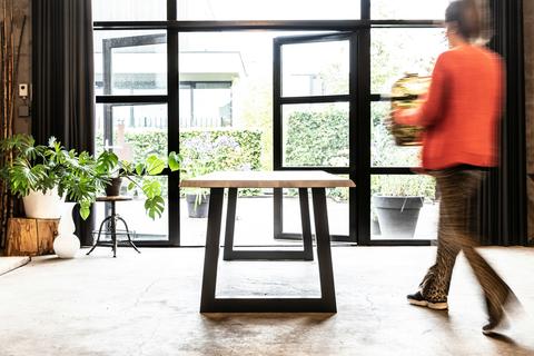 Massief houten tafelblad op zwart stalen onderstel in een licht interieur