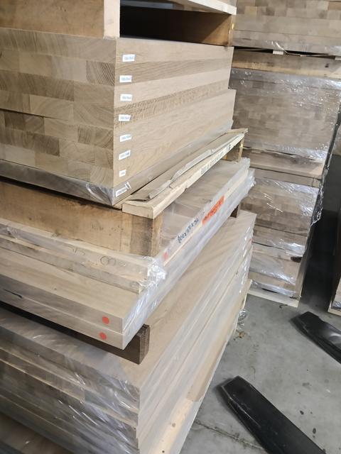 Gestapelde massief houten timmerpanelen op pallets in het magazijn, klaar voor maatwerk