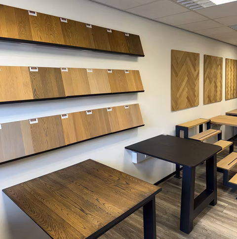 Showroom met massief eiken panelen, houtstalen en houten tafelbladen op zwarte onderstellen