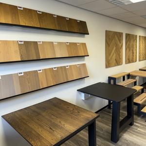 Showroom met massief eiken panelen, houtstalen en houten tafelbladen op zwarte onderstellen