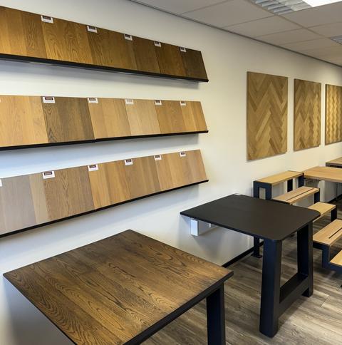 Showroom met massief eiken panelen, houtstalen en houten tafelbladen op zwarte onderstellen