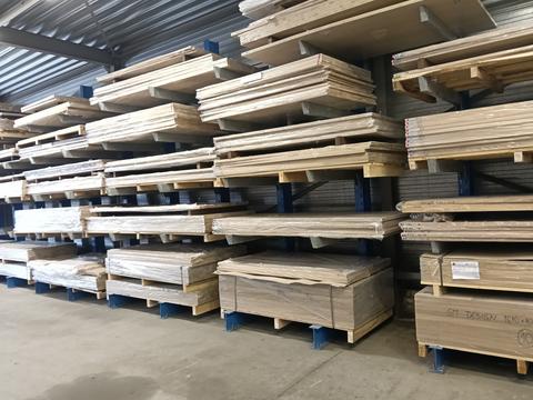 Stapels massief houten timmerpanelen op pallets en stellingen in een houtmagazijn