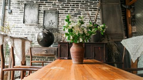 Massief kersenhouten tafelblad in rustiek interieur met bloemenvaas en houten stoelen