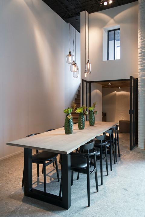 Lange massief houten tafel met zwart stalen onderstel en stoelen in industrieel interieur